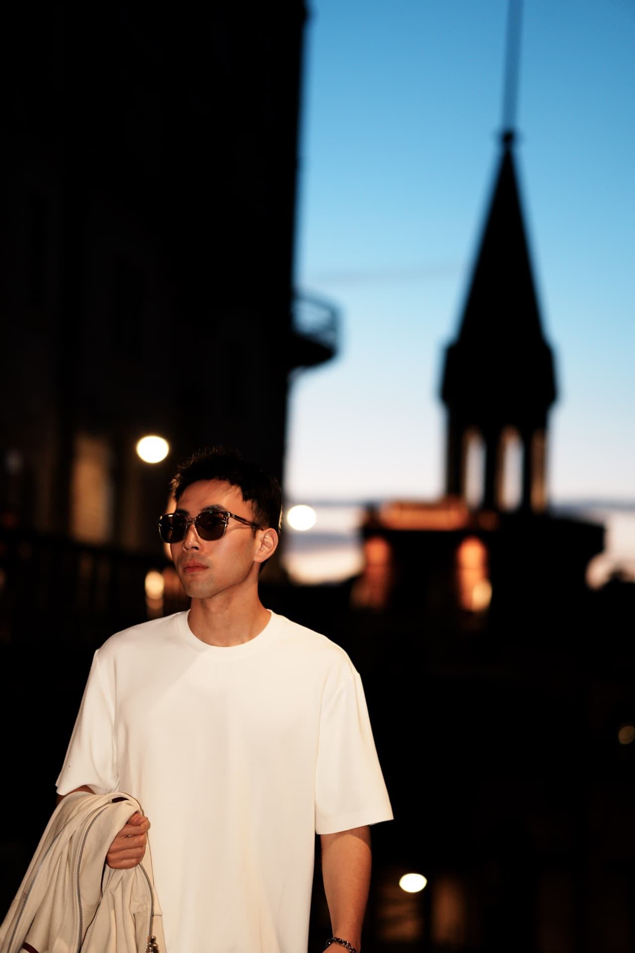 Man at dusk with a Stockholm church spire silhouetted behind him